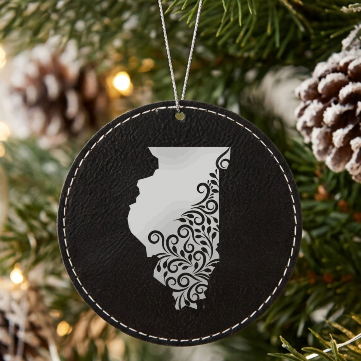 Black leatherette round Christmas ornament laser engraved with the Illinois Floral Damask design, hanging on a tree