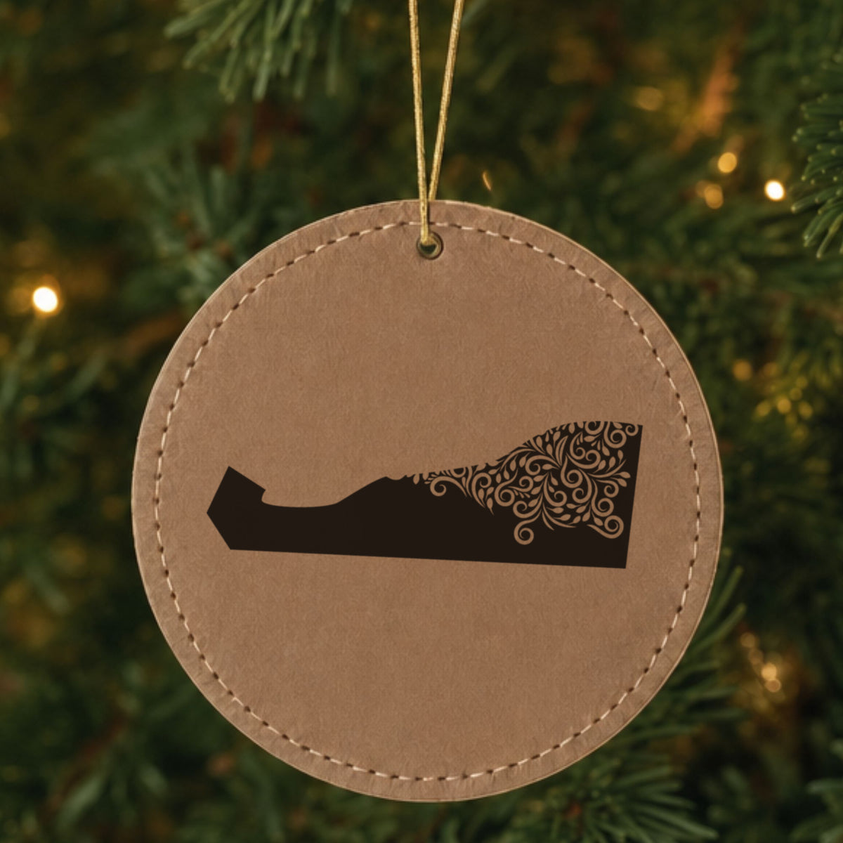 Brown leatherette round Christmas ornament laser engraved with the Delaware Floral Damask design, hanging on a tree
