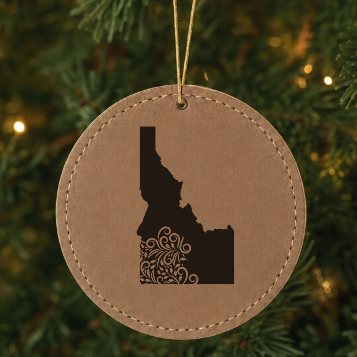 Brown leatherette round Christmas ornament laser engraved with the Idaho Floral Damask design, hanging on a tree