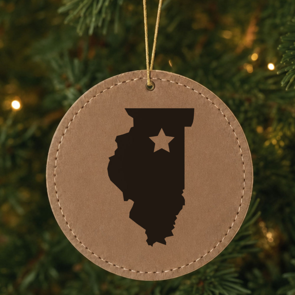Brown leatherette round Christmas ornament laser engraved with the Illinois Star Accent design, hanging on a tree