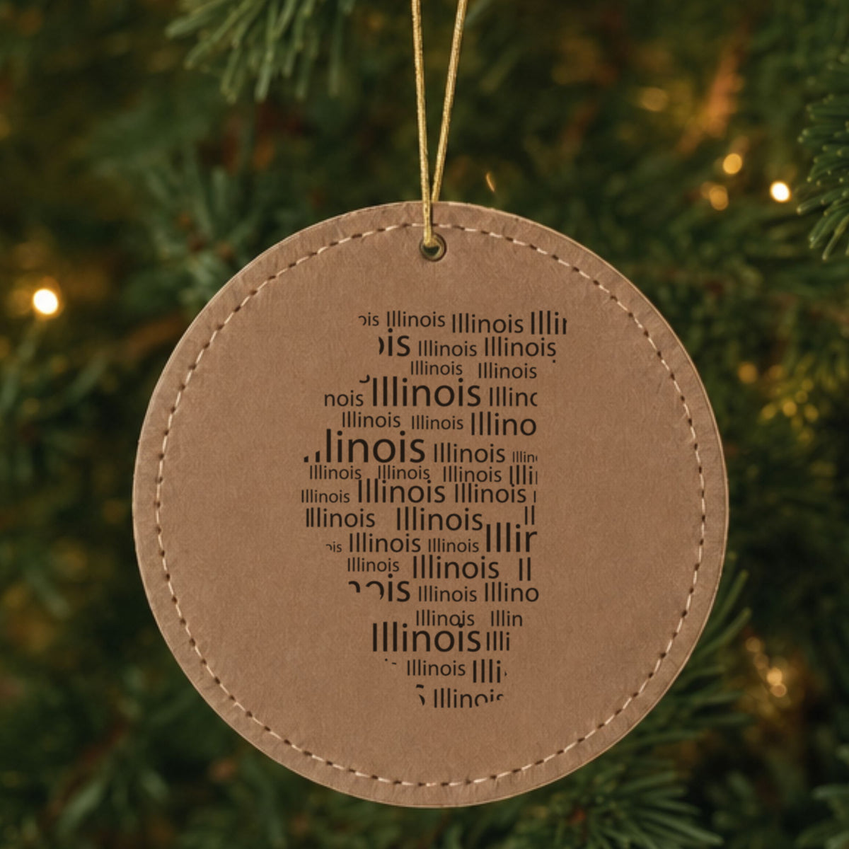 Brown leatherette round Christmas ornament laser engraved with the Illinois Word Cloud design, hanging on a tree