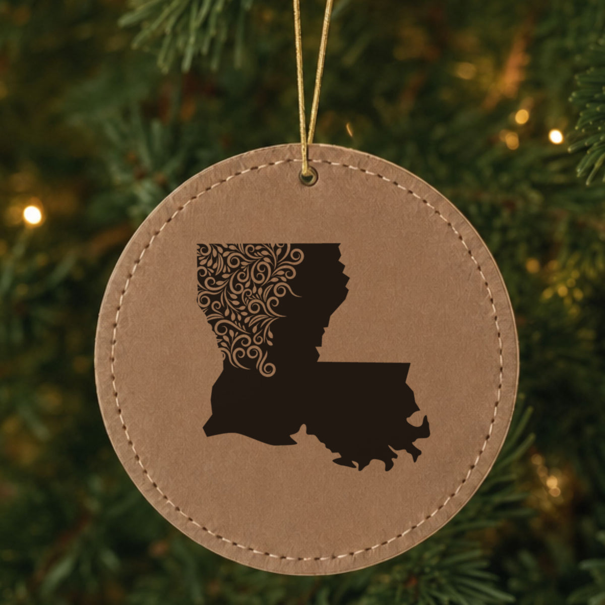Brown leatherette round Christmas ornament laser engraved with the Louisiana Floral Damask design, hanging on a tree