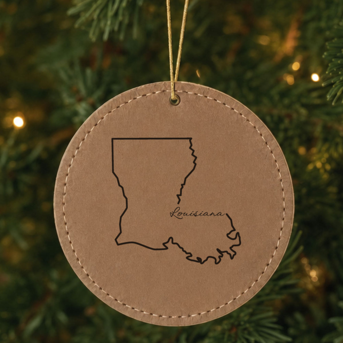 Brown leatherette round Christmas ornament laser engraved with the Louisiana Louisiana Script design, hanging on a tree