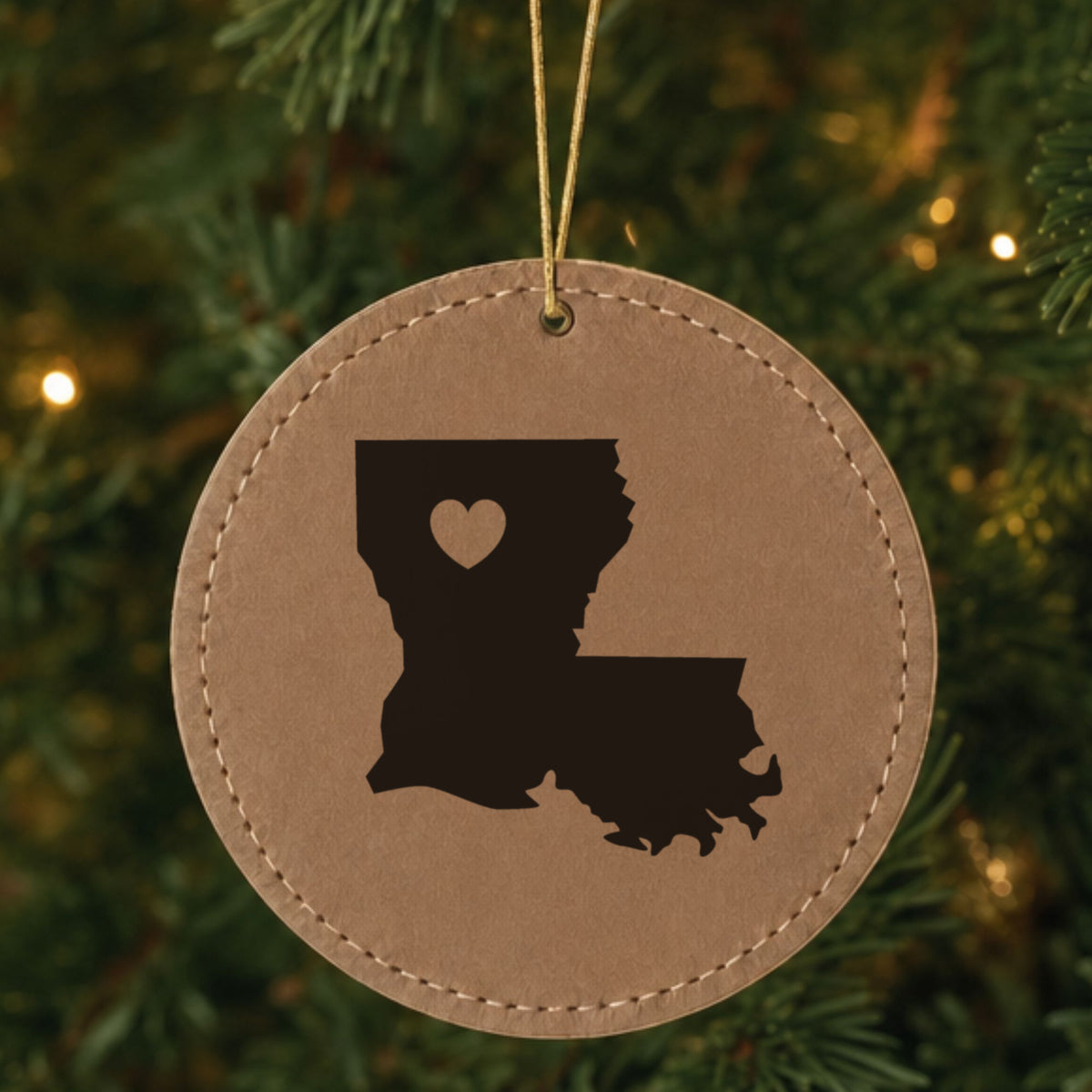 Brown leatherette round Christmas ornament laser engraved with the Louisiana Heart Accent design, hanging on a tree