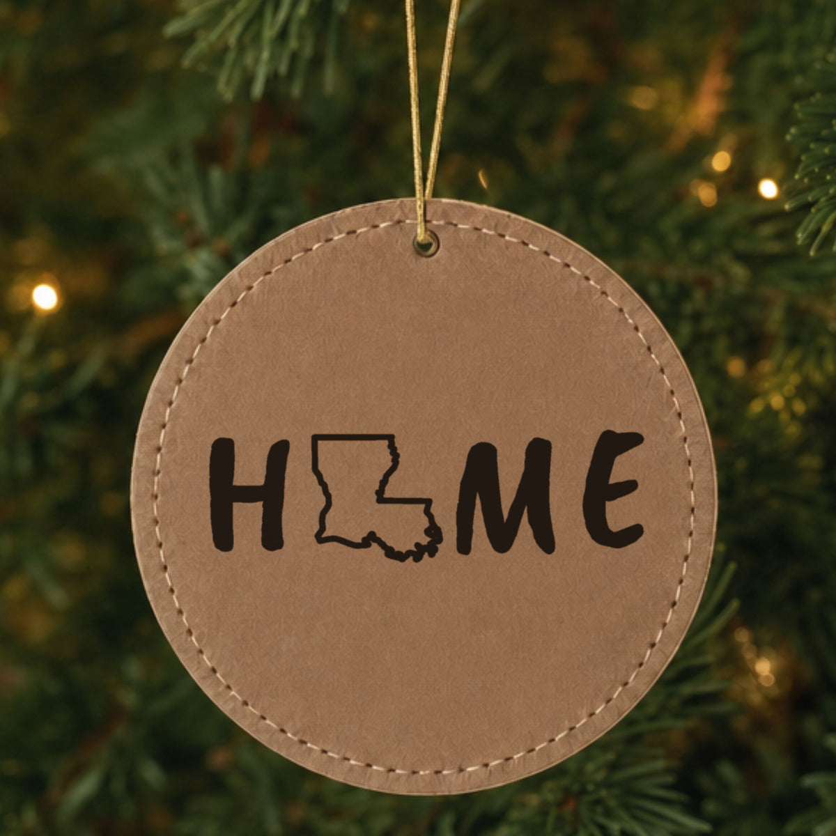 Brown leatherette round Christmas ornament laser engraved with the Louisiana HOME Outline design, hanging on a tree