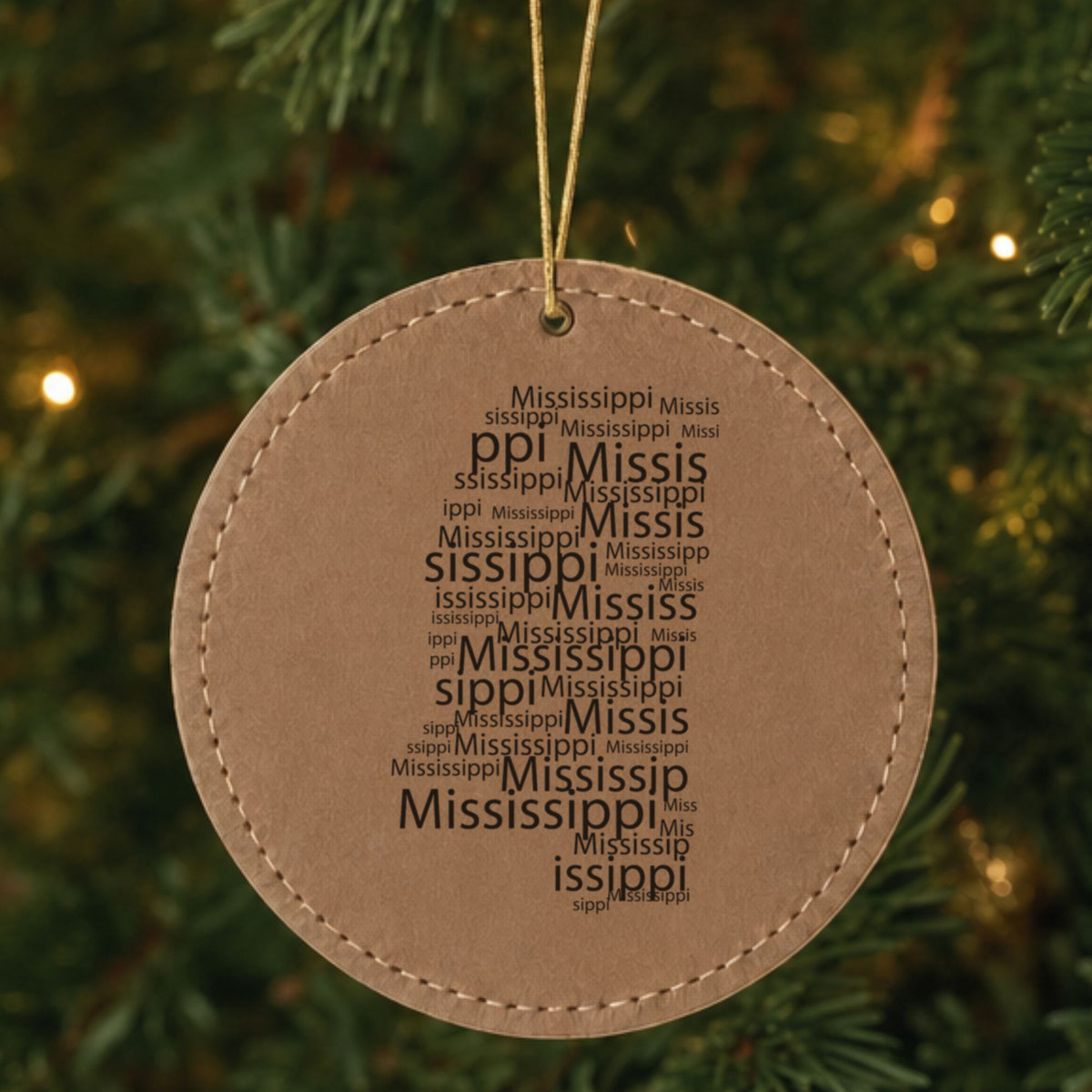Brown leatherette round Christmas ornament laser engraved with the Mississippi Word Cloud design, hanging on a tree