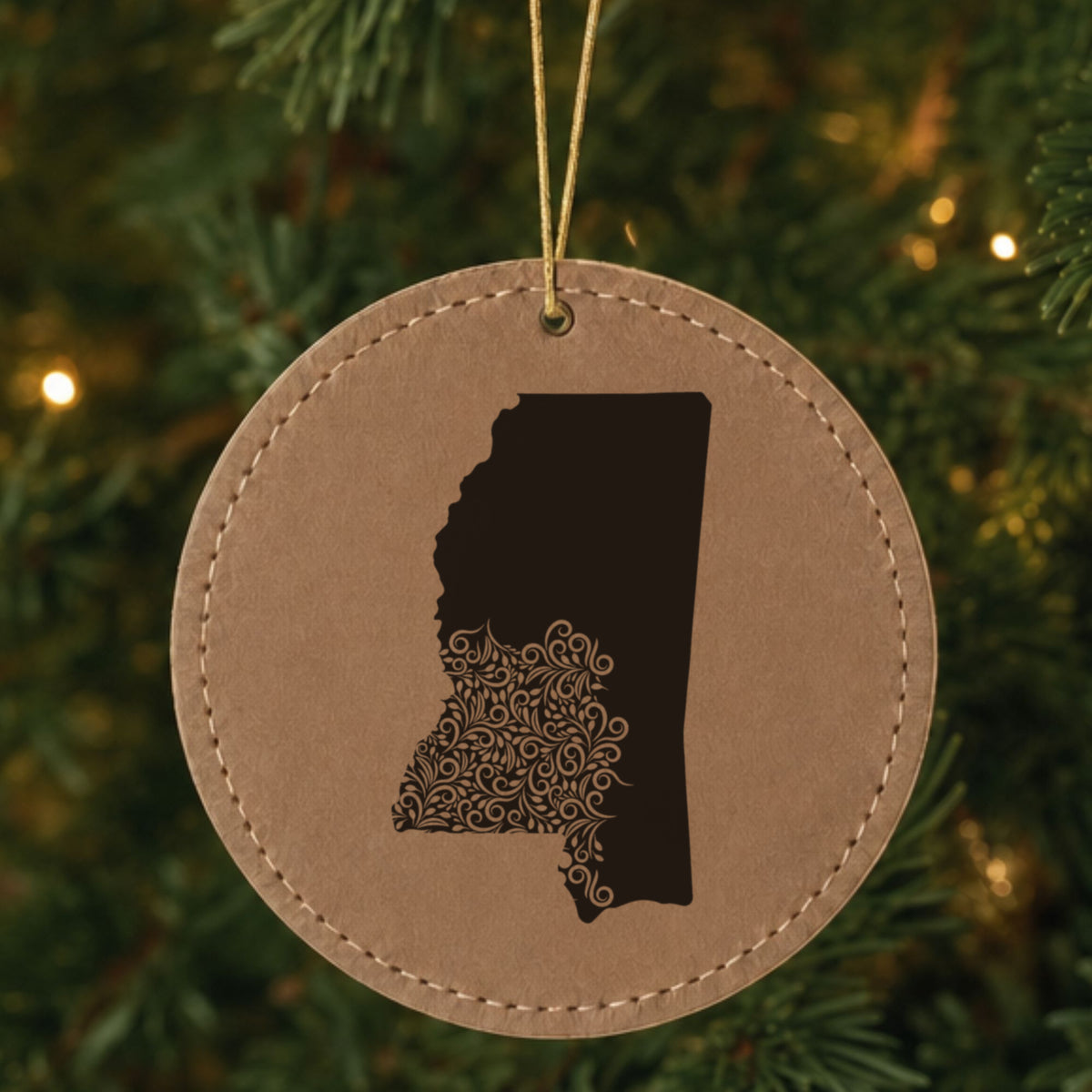 Brown leatherette round Christmas ornament laser engraved with the Mississippi Floral Damask design, hanging on a tree
