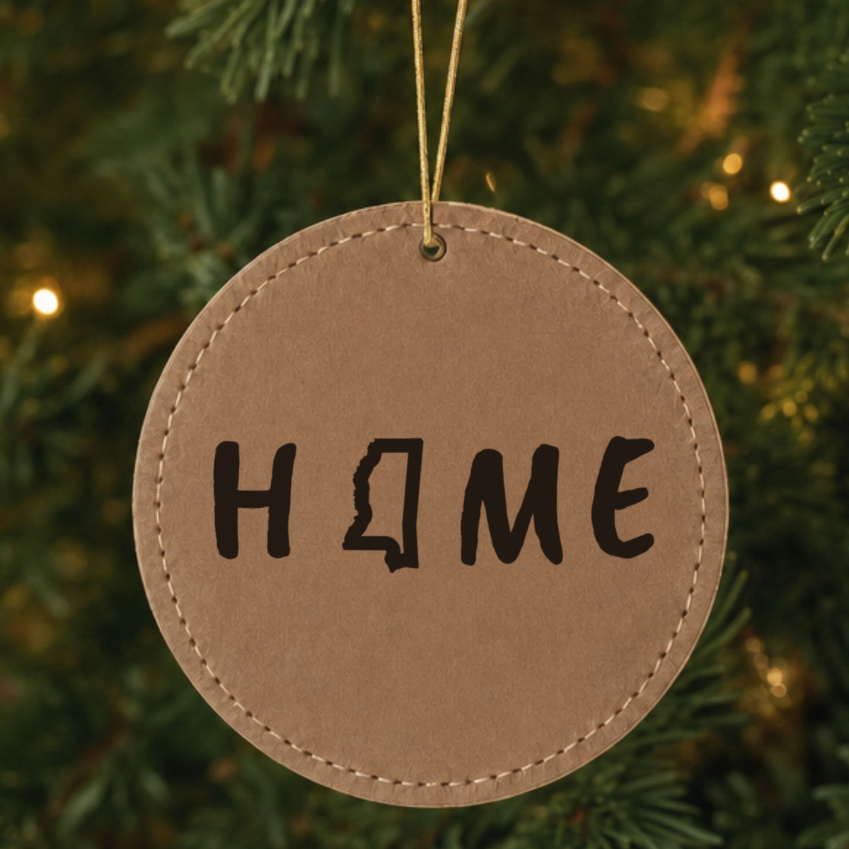 Brown leatherette round Christmas ornament laser engraved with the Mississippi HOME Outline design, hanging on a tree