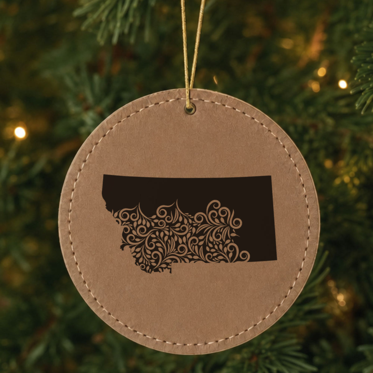 Brown leatherette round Christmas ornament laser engraved with the Montana Floral Damask design, hanging on a tree