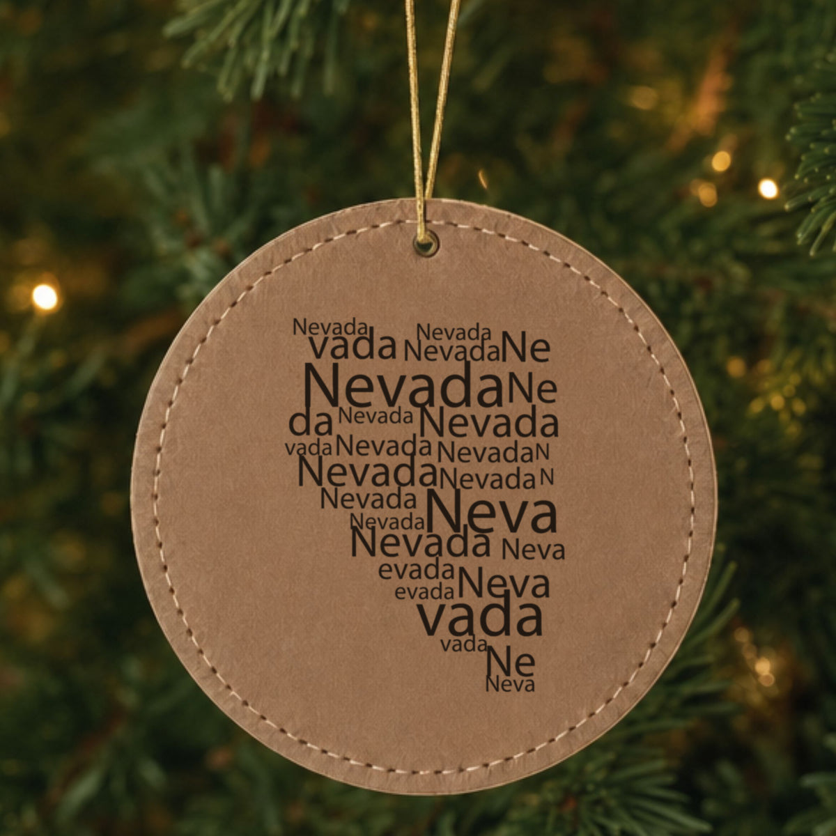 Brown leatherette round Christmas ornament laser engraved with the Nevada Word Cloud design, hanging on a tree