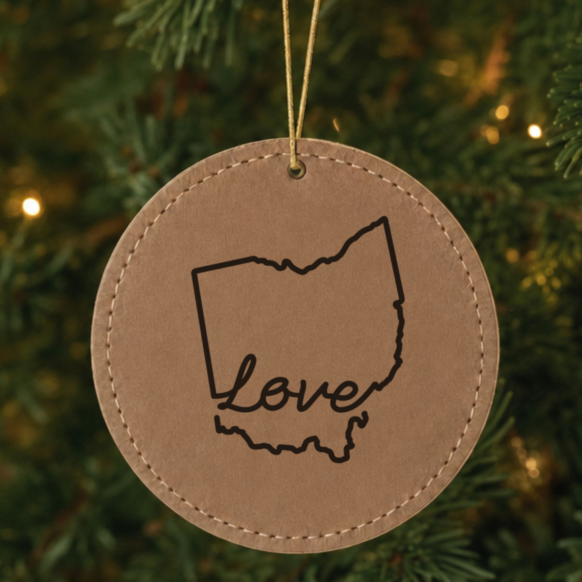 Brown leatherette round Christmas ornament laser engraved with the Ohio Hand-Drawn Love design, hanging on a tree