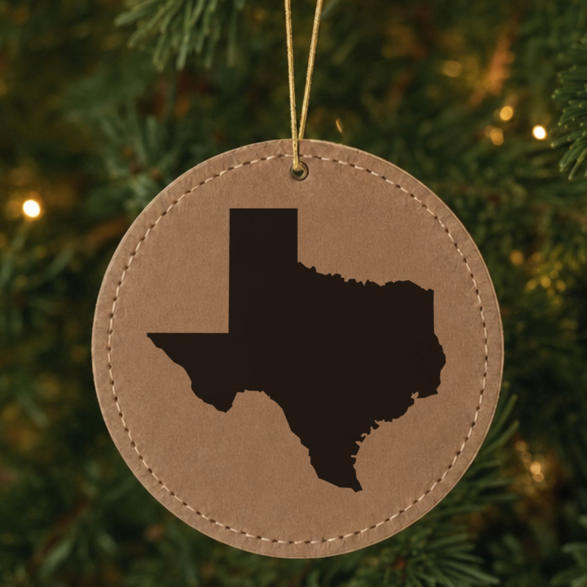 Brown leatherette round Christmas ornament laser engraved with the Texas Engraved State design, hanging on a tree