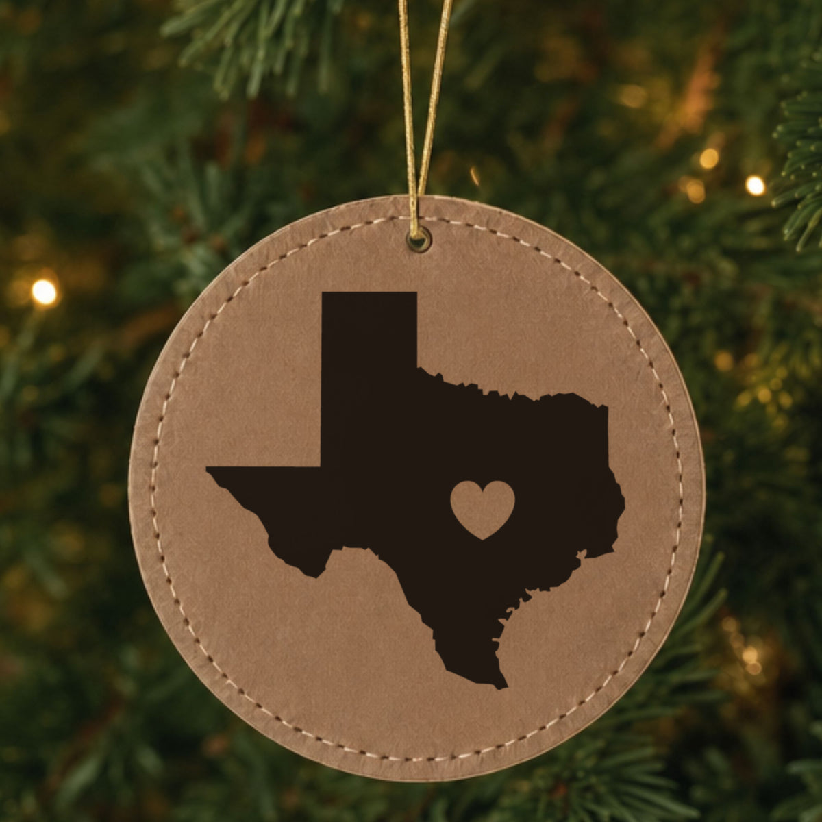 Brown leatherette round Christmas ornament laser engraved with the Texas Heart Accent design, hanging on a tree