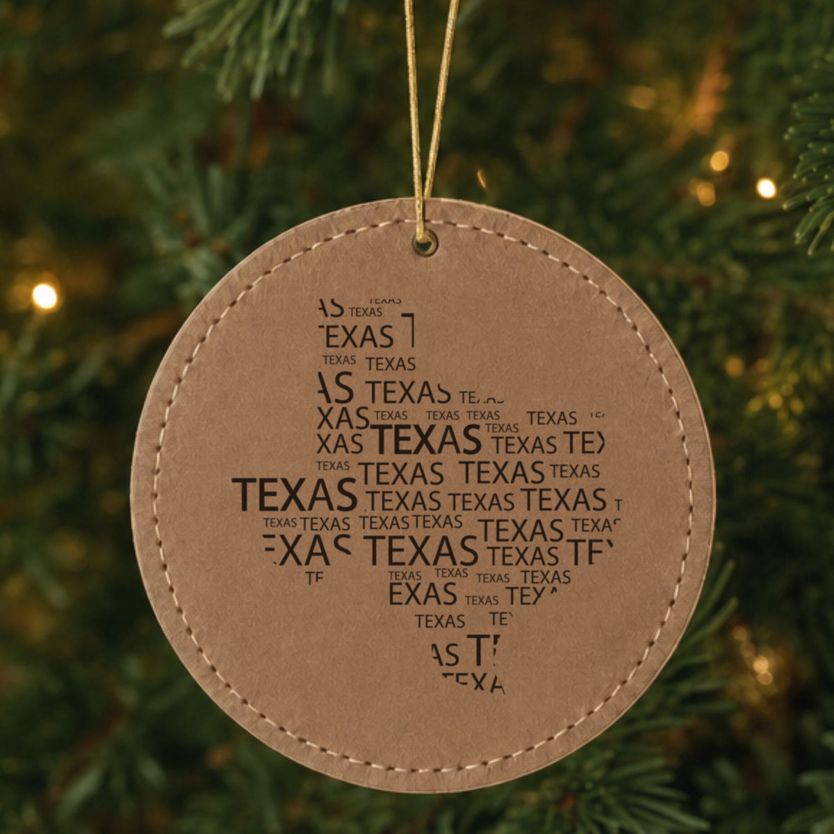 Brown leatherette round Christmas ornament laser engraved with the Texas Word Cloud design, hanging on a tree