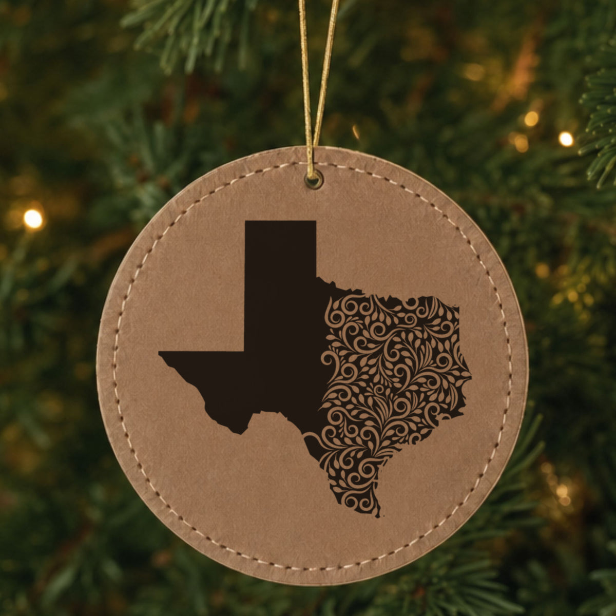 Brown leatherette round Christmas ornament laser engraved with the Texas Floral Damask design, hanging on a tree