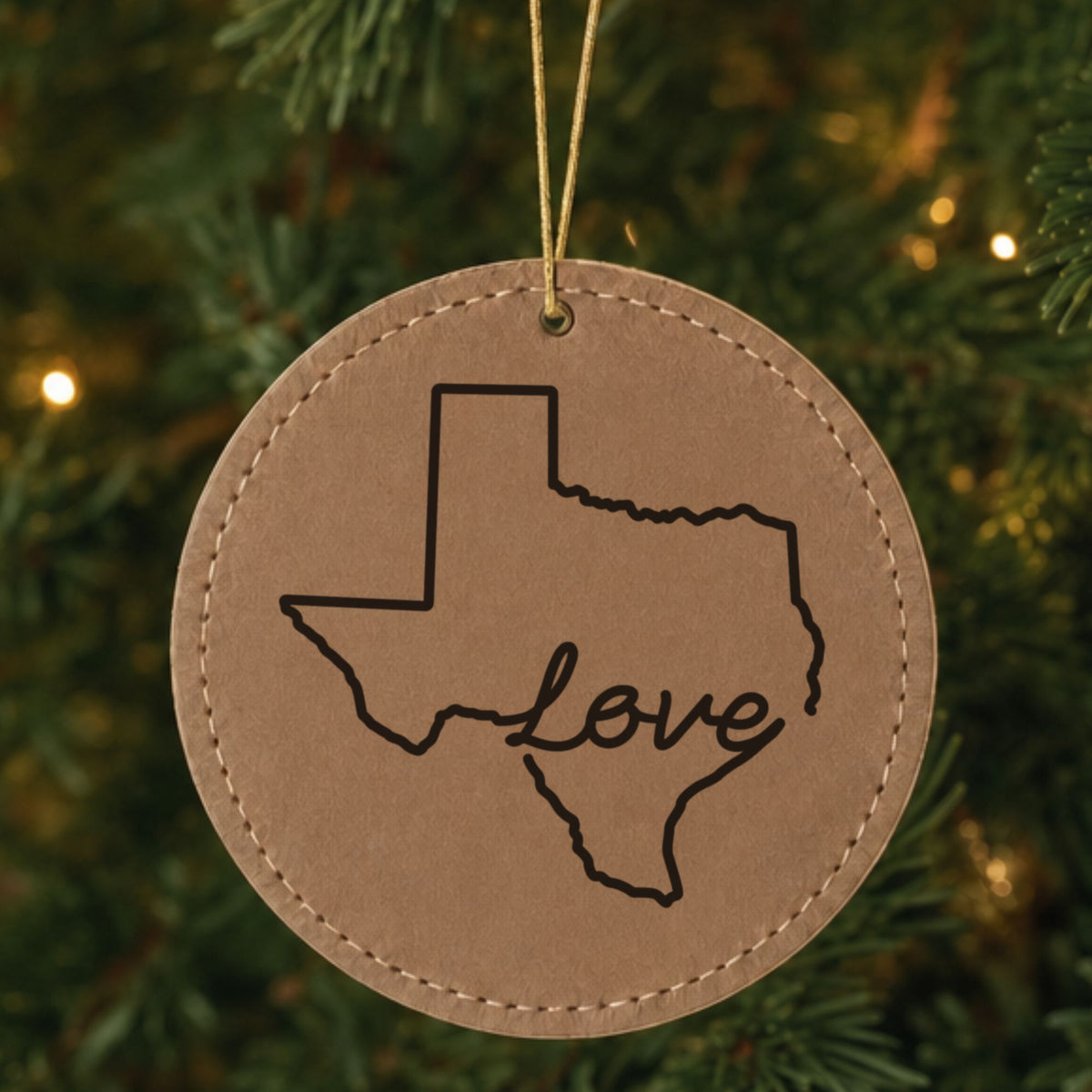 Brown leatherette round Christmas ornament laser engraved with the Texas Hand-Drawn Love design, hanging on a tree