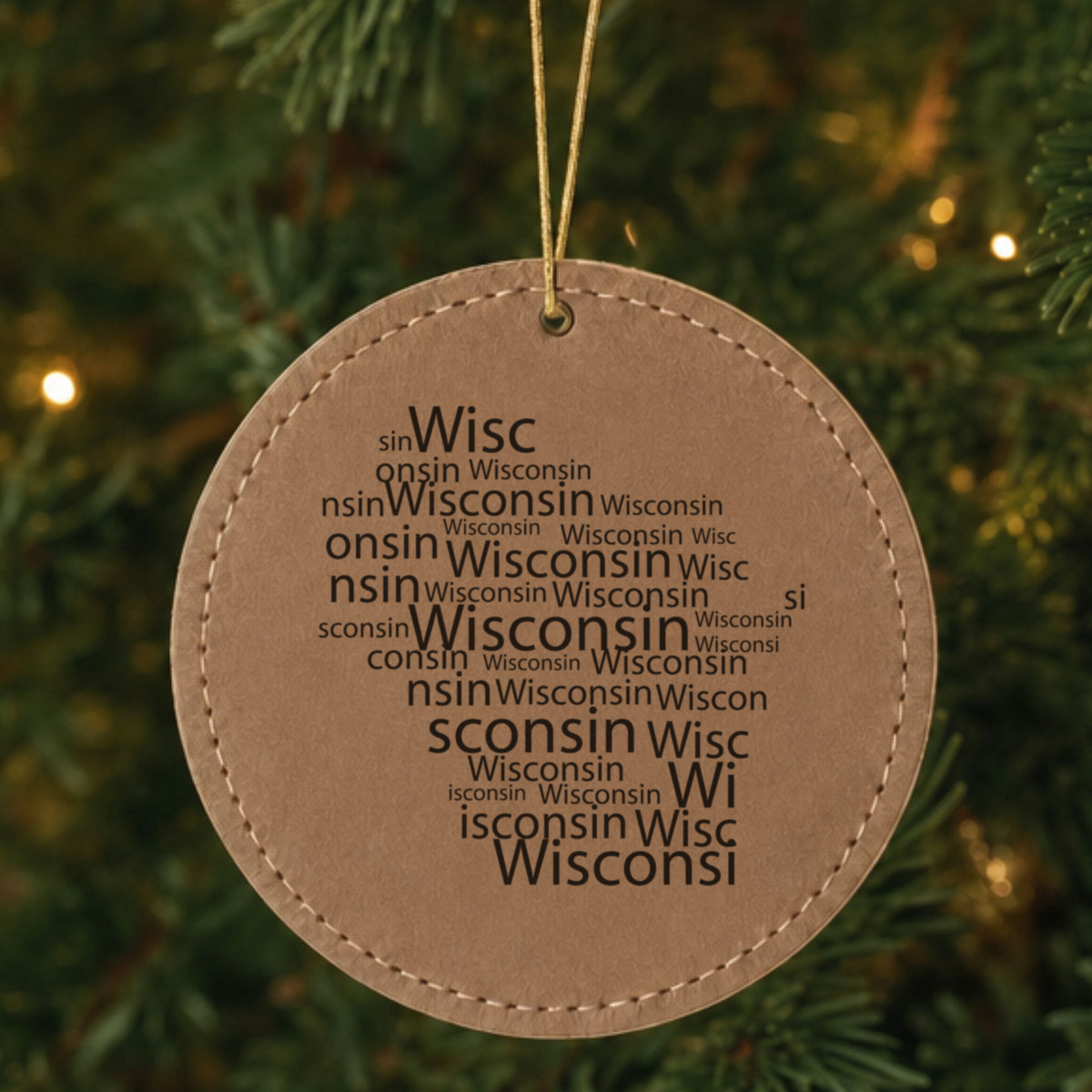Brown leatherette round Christmas ornament laser engraved with the Wisconsin Word Cloud design, hanging on a tree