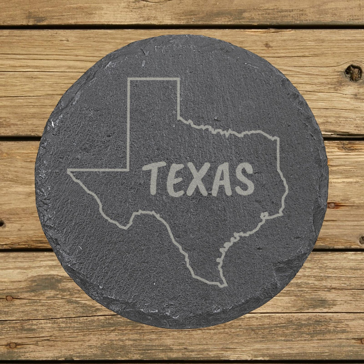 Texas round slate coaster engraved with the state outline and TEXAS in hand-drawn brush lettering