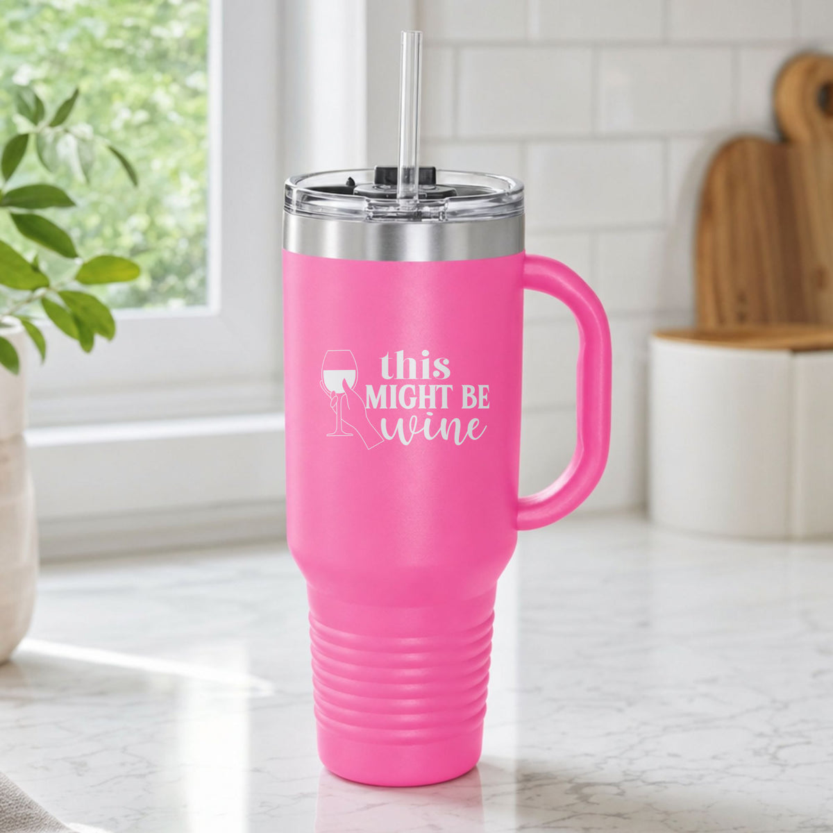 Pink 40 oz tumbler with handle and straw laser engraved with "This Might Be Wine", on a kitchen counter