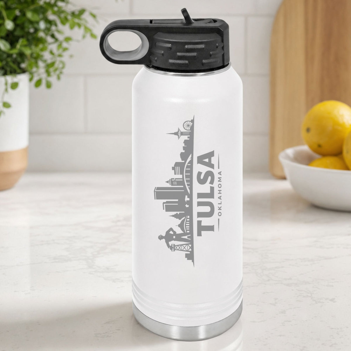 White 32 oz insulated water bottle laser engraved with the Tulsa, Oklahoma skyline running up the side, standing on a kitchen counter