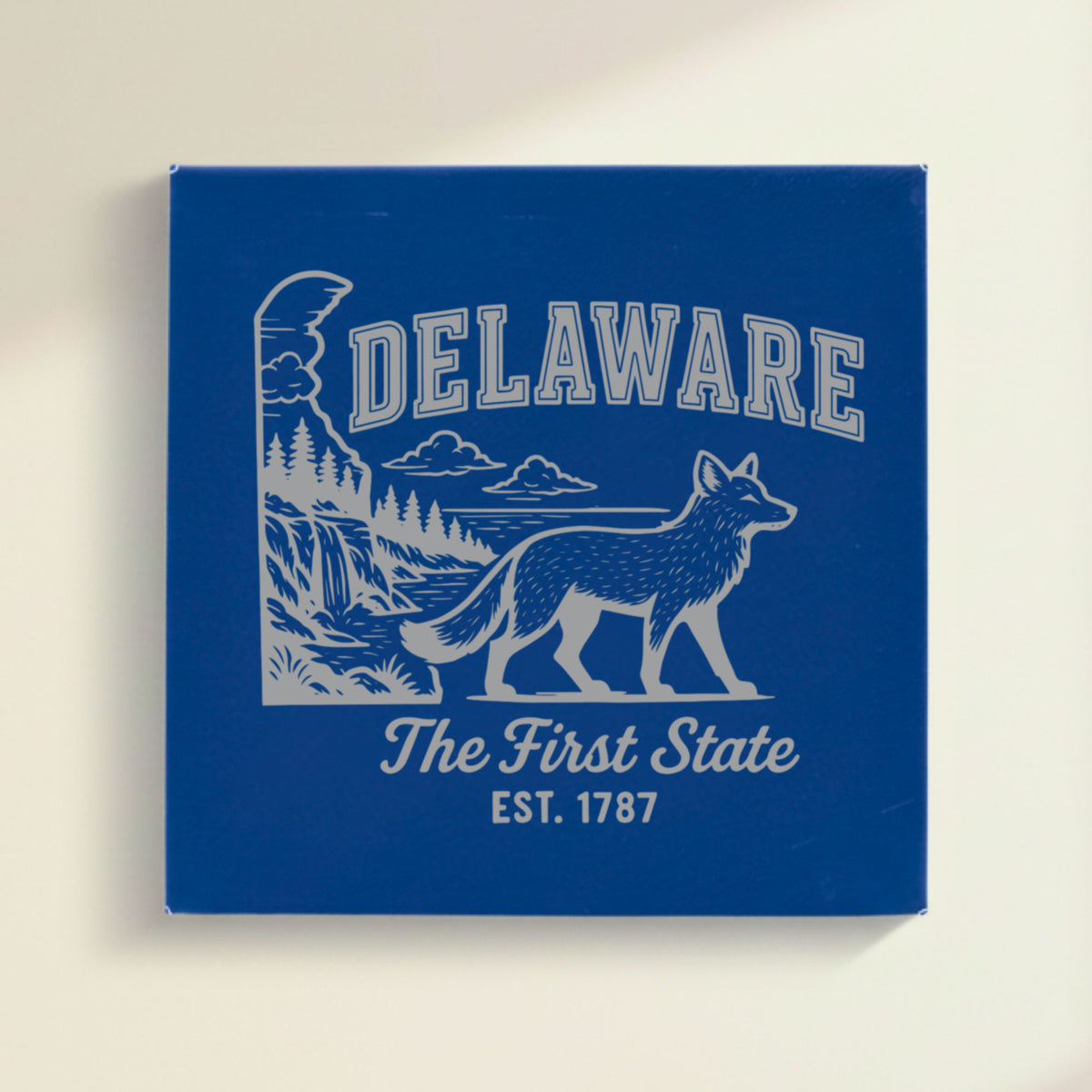 Close up of the Delaware design engraved on Blue leatherette: a gray fox, a waterfall and pine forest, "The First State", EST. 1787