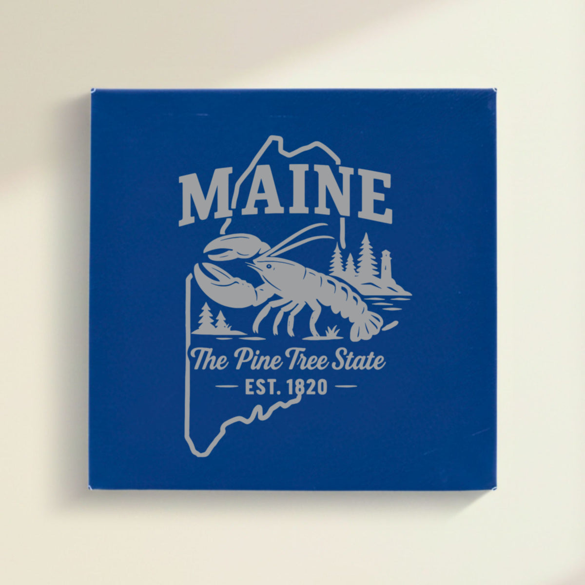 Close up of the Maine design engraved on Blue leatherette: a lobster, pines and a lighthouse, "The Pine Tree State", EST. 1820