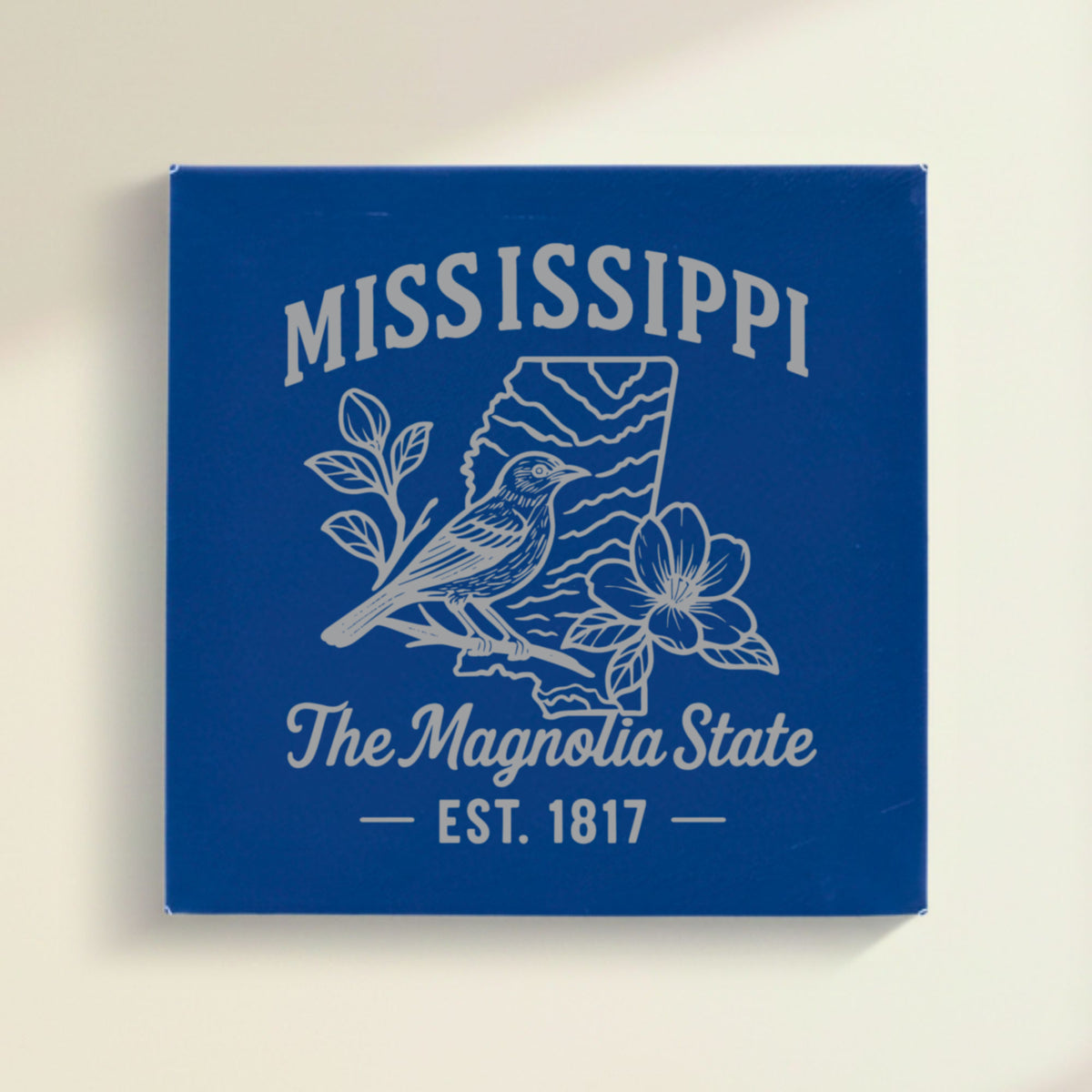 Close up of the Mississippi design engraved on Blue leatherette: a mockingbird and magnolia blossoms, "The Magnolia State", EST. 1817