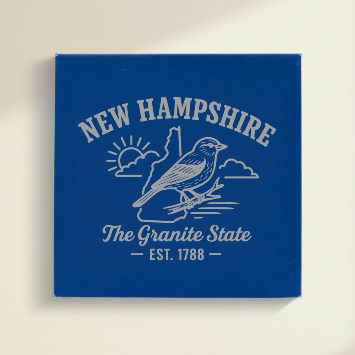 Close up of the New Hampshire design engraved on Blue leatherette: a purple finch, "The Granite State", EST. 1788
