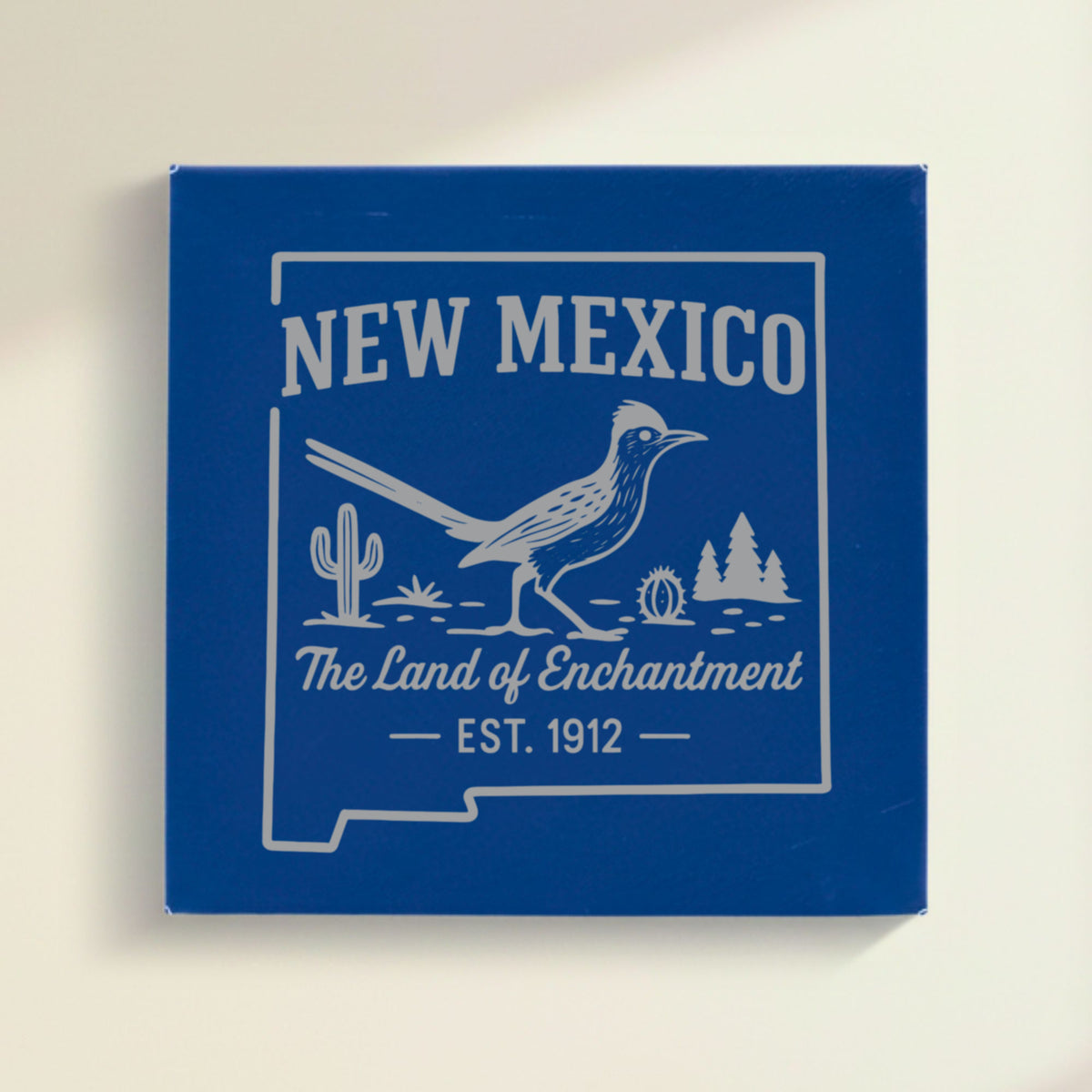 Close up of the New Mexico design engraved on Blue leatherette: a roadrunner, cactus and pines, "The Land of Enchantment", EST. 1912