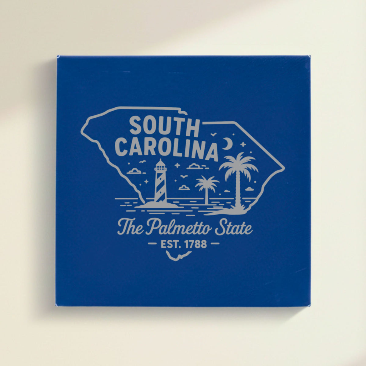 Close up of the South Carolina design engraved on Blue leatherette: a striped lighthouse, palm trees and a beach under a crescent moon, "The Palmetto State", EST. 1788