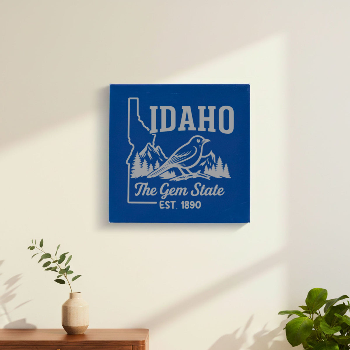 Blue leatherette wall sign engraved with an Idaho design of a mountain bluebird, mountains and pines, hanging on a wall