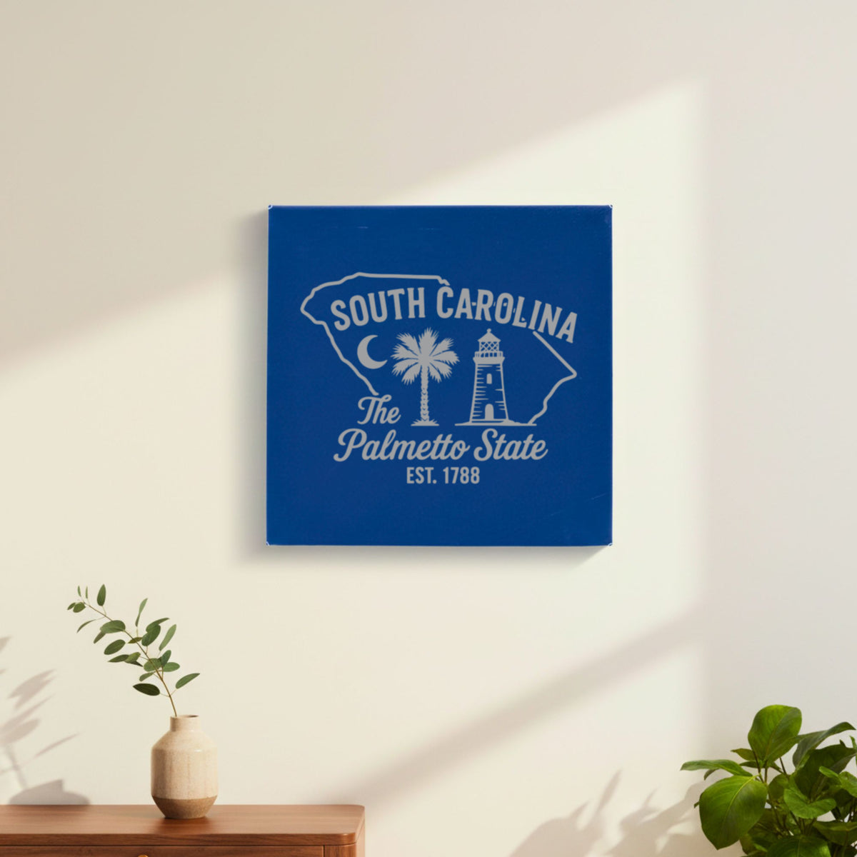 Blue leatherette wall sign engraved with a South Carolina design of a crescent moon, a palmetto tree and a lighthouse, hanging on a wall