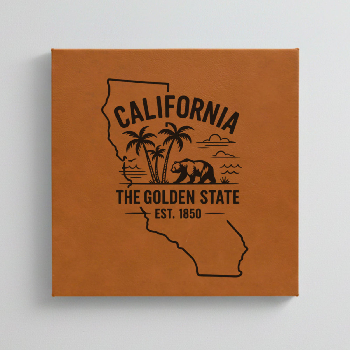 Close up of the California design engraved on Brown leatherette: palm trees, the ocean and a grizzly bear, "The Golden State", EST. 1850