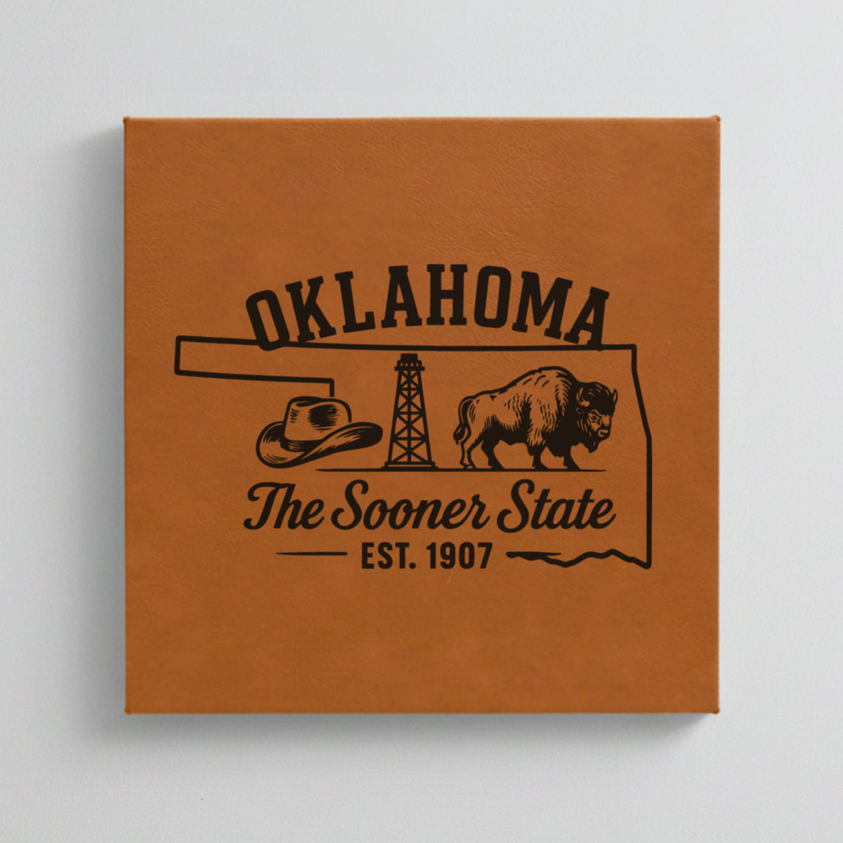 Close up of the Oklahoma design engraved on Brown leatherette: a cowboy hat, an oil derrick and a bison, "The Sooner State", EST. 1907