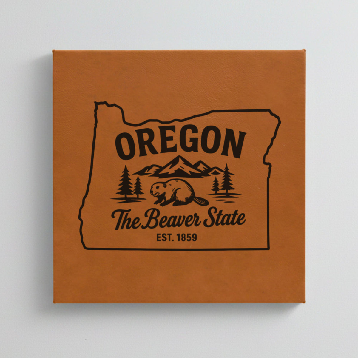 Close up of the Oregon design engraved on Brown leatherette: a beaver, mountains and pines, "The Beaver State", EST. 1859