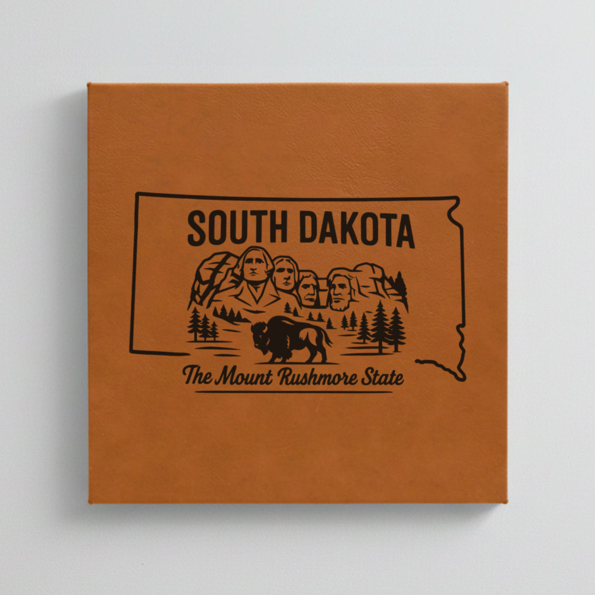 Close up of the South Dakota design engraved on Brown leatherette: Mount Rushmore and a bison, "The Mount Rushmore State"