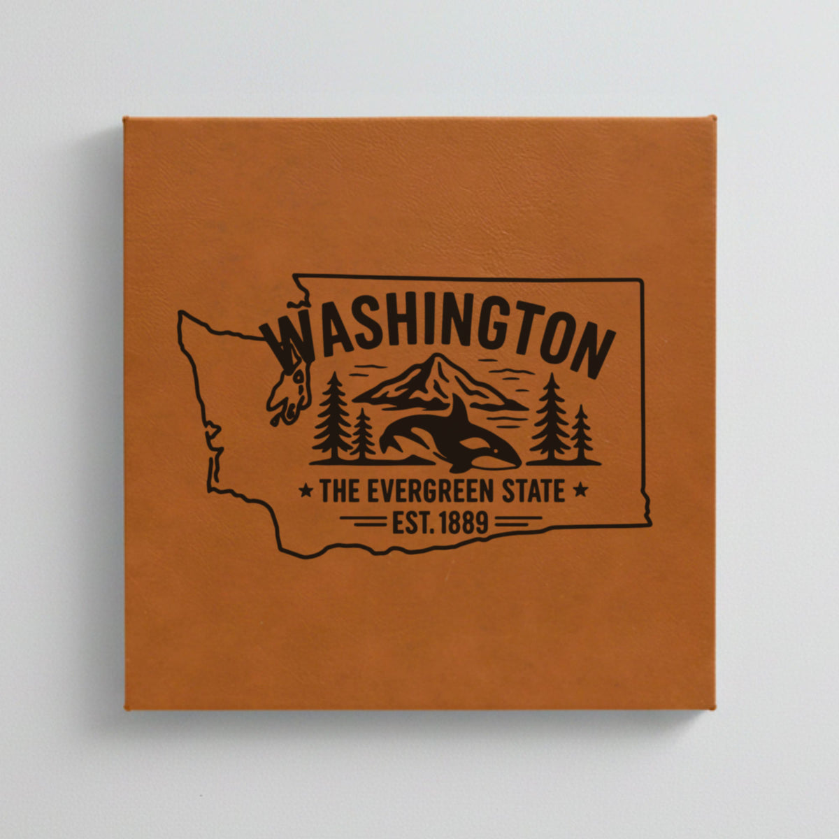 Close up of the Washington design engraved on Brown leatherette: an orca, Mount Rainier and evergreens, "The Evergreen State", EST. 1889