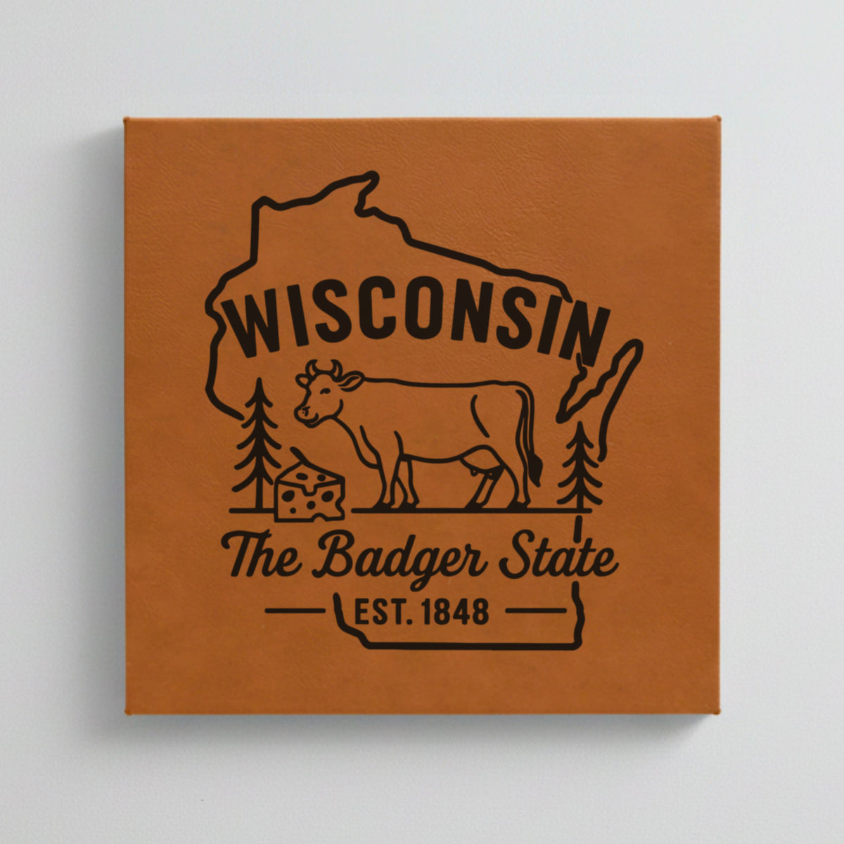 Close up of the Wisconsin design engraved on Brown leatherette: a dairy cow and a wedge of cheese, "The Badger State", EST. 1848