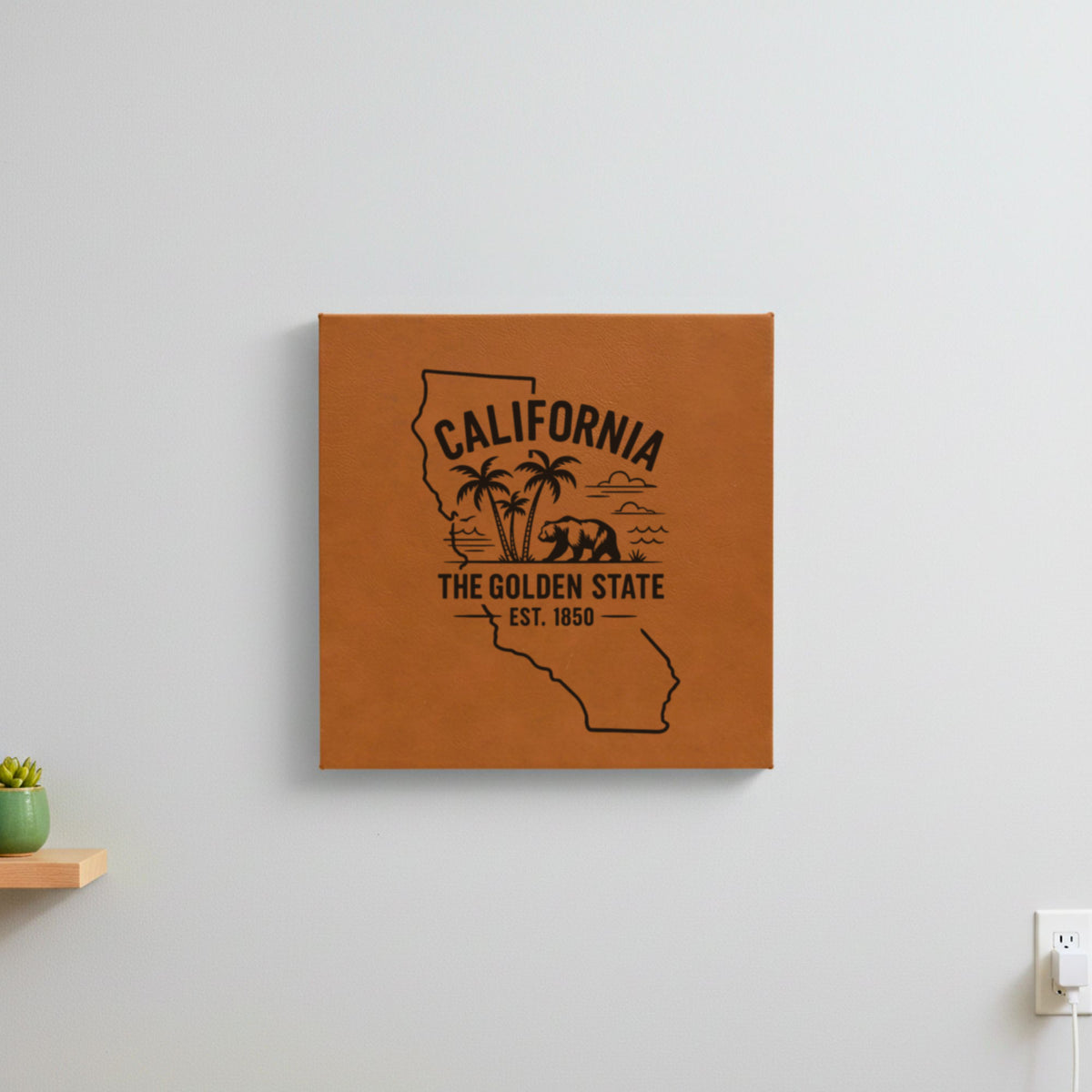 Brown leatherette wall sign engraved with a California design of palm trees, the ocean and a grizzly bear, hanging on a wall