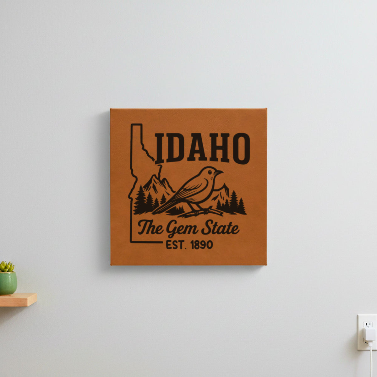 Brown leatherette wall sign engraved with an Idaho design of a mountain bluebird, mountains and pines, hanging on a wall