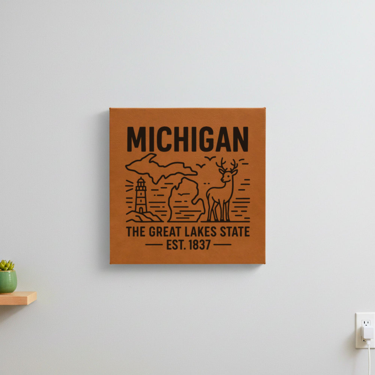 Brown leatherette wall sign engraved with a Michigan design of a lighthouse, a whitetail buck and both peninsulas, hanging on a wall