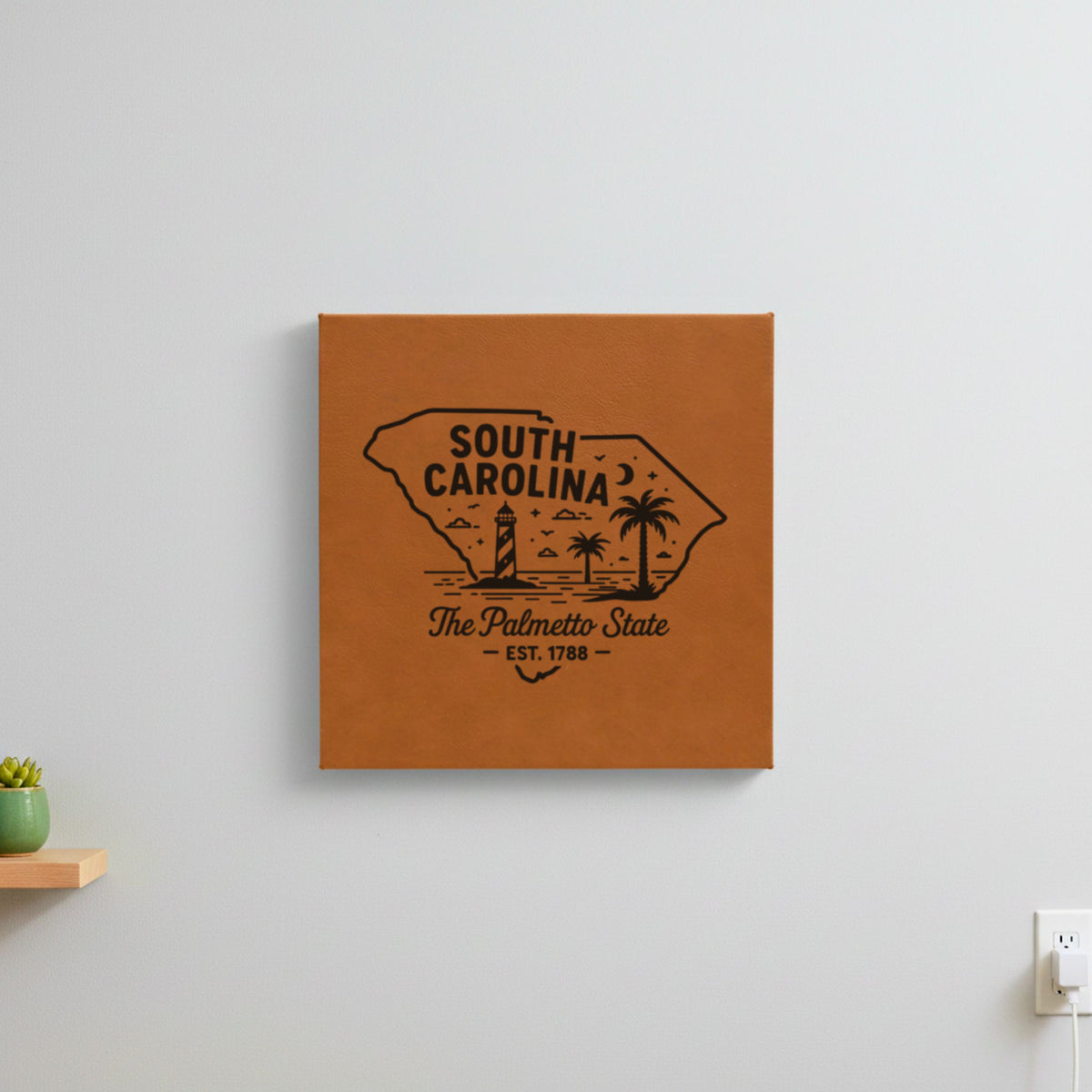 Brown leatherette wall sign engraved with a South Carolina design of a striped lighthouse, palm trees and a beach under a crescent moon, hanging on a wall