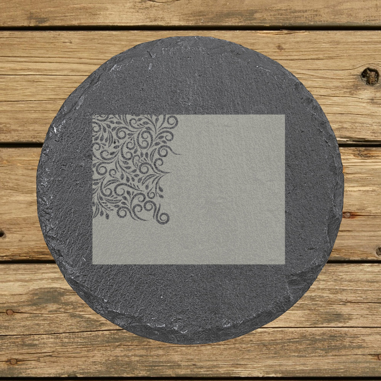 Wyoming round slate coaster engraved with the state shape in ornate floral scrollwork