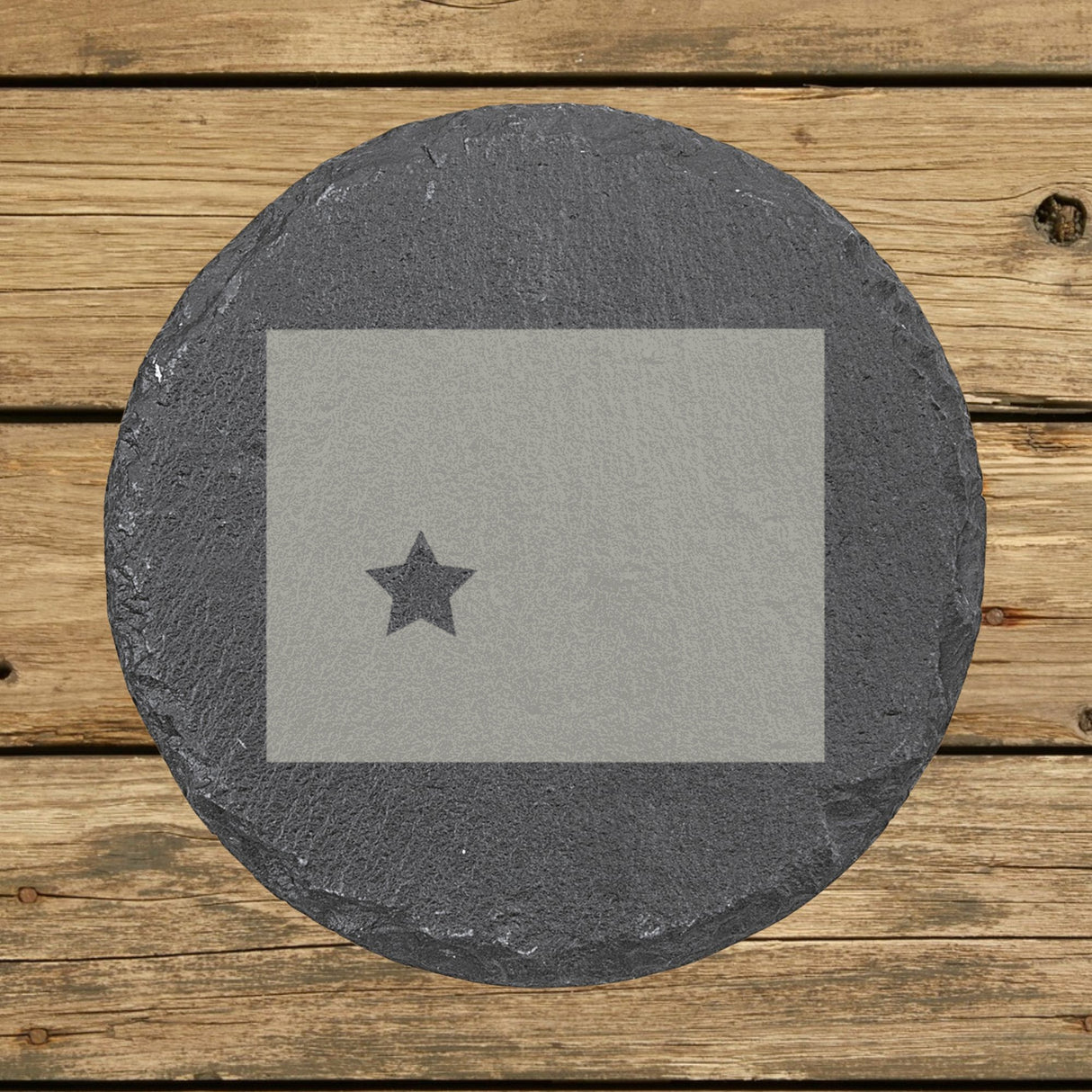 Wyoming round slate coaster engraved with the state shape and a star