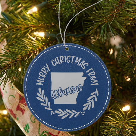 Blue leatherette round Christmas ornament engraved Merry Christmas From Arkansas, with the state shape in a laurel wreath