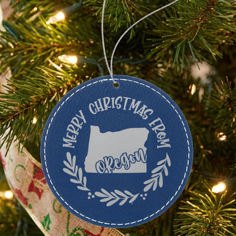 Blue leatherette Merry Christmas From Oregon ornament engraved with the state shape