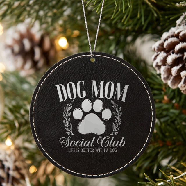 Black leatherette Christmas ornament engraved with a Dog Mom Social Club crest design with a paw print and laurel wreath