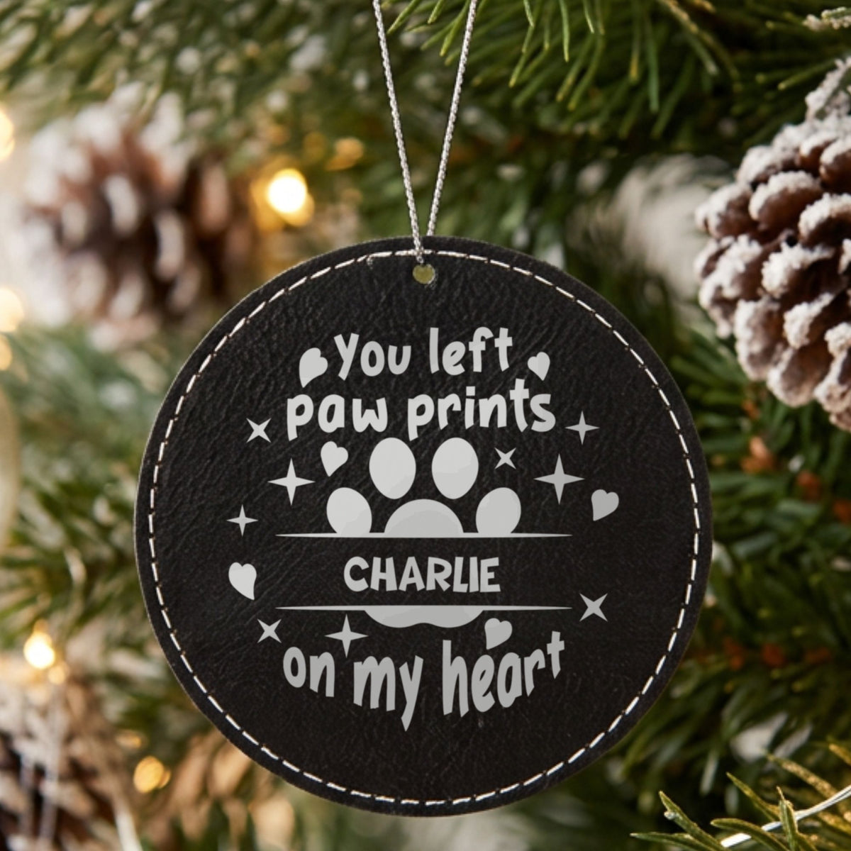 Black leatherette Christmas ornament engraved with the You Left Paw Prints on My Heart design and a sample pet name