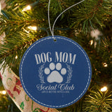 Blue leatherette Christmas ornament engraved with a Dog Mom Social Club crest design with a paw print and laurel wreath