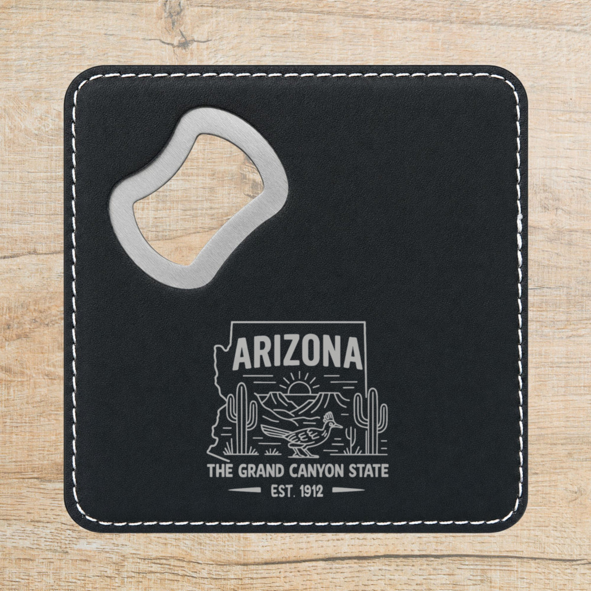Black leatherette bottle opener coaster laser engraved with an Arizona design of saguaro cactus, a roadrunner and the Grand Canyon at sunrise